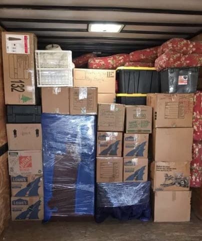 The inside of a loaded truck: cartons, a shrink-wrapped mattress and blanketed furniture stacked wall to wall