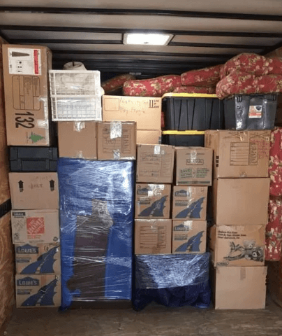 The inside of a loaded truck: cartons, a shrink-wrapped mattress and blanketed furniture stacked wall to wall