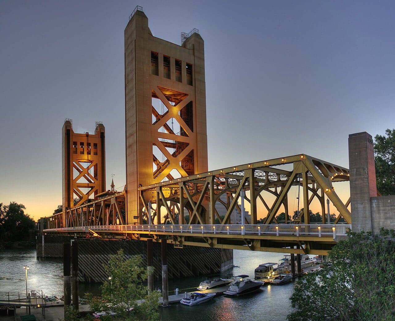 The Tower Bridge over the Sacramento River at dusk, its towers and trusses lit gold
